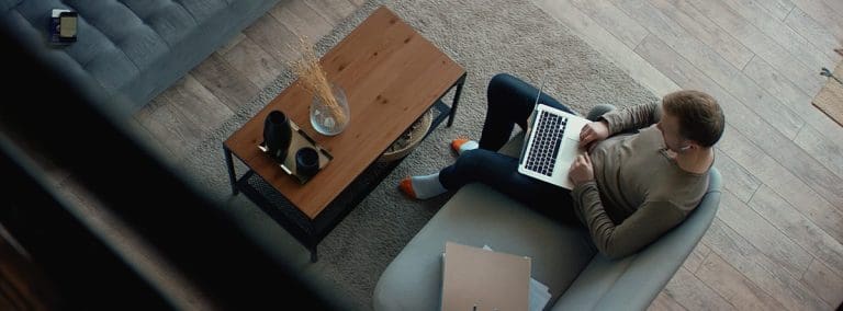Overhead view of man sitting on couch on computer
