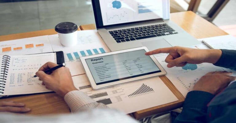 Business partnership coworkers using a tablet to analysis graph company financial budget report and cost work progress and planning for future in office room.