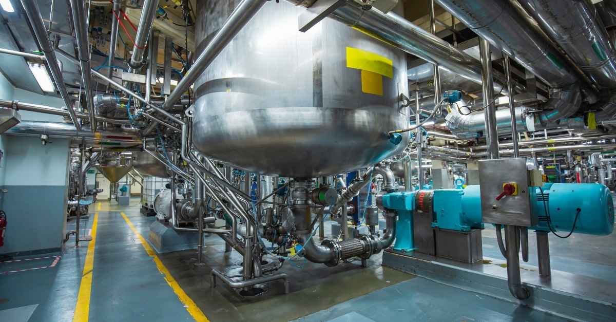 Stainless steel vertical chemical tanks on a chemical manufacturing floor.